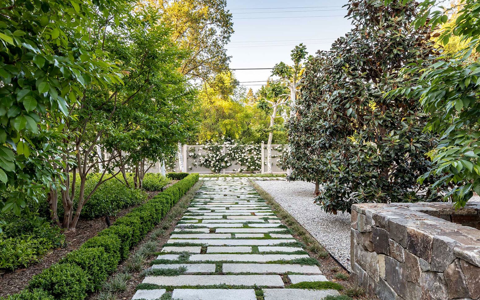 Stone walkway to fence with white roses